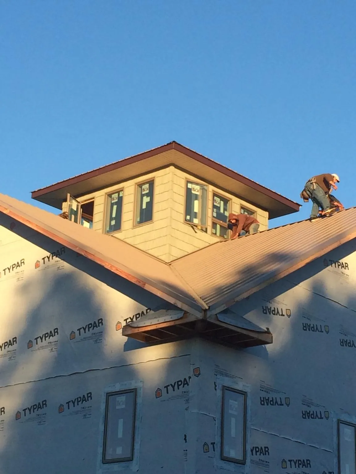 Roofers working around a rooftop cupola on a new metal roof at sunset — Roof Waterproofing in Haverhill by Roofing Brothers